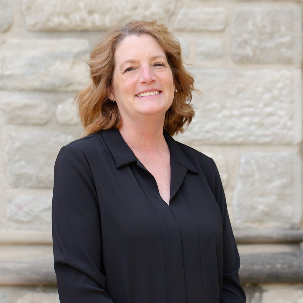 A woman with short blond hair wearing a long sleeve black shirt.