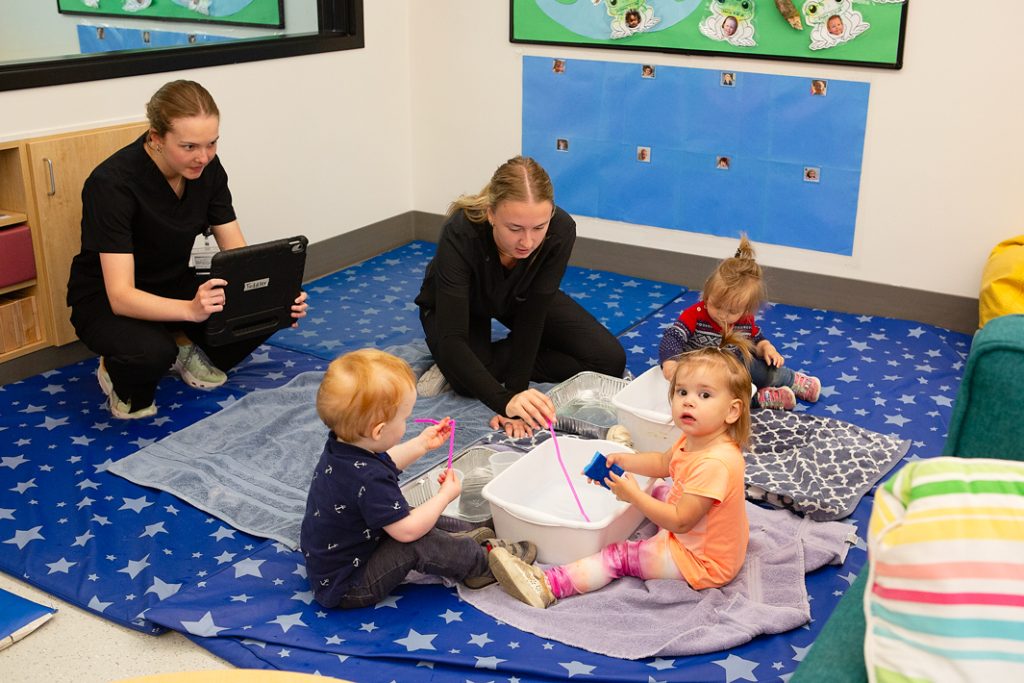 Two students lead a provocation exercise with toddlers where they explore water.