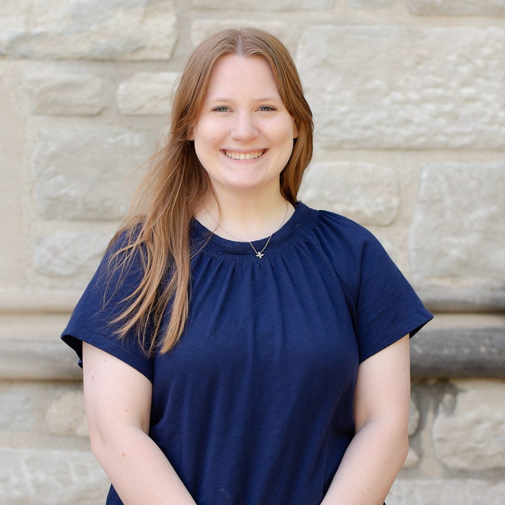 A woman with long red hair wearing a blue shirt.