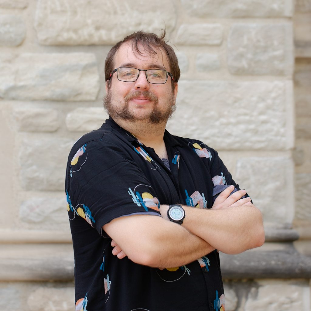 A man with glasses and a black short sleeve shirt.