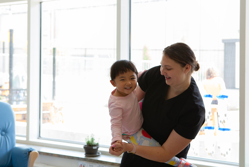 An early childhood professional dances with a young girl.
